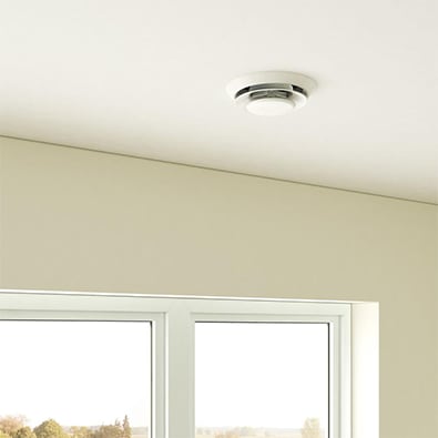 A room with two windows, beige walls, a white ceiling and a white ceiling diffuser.