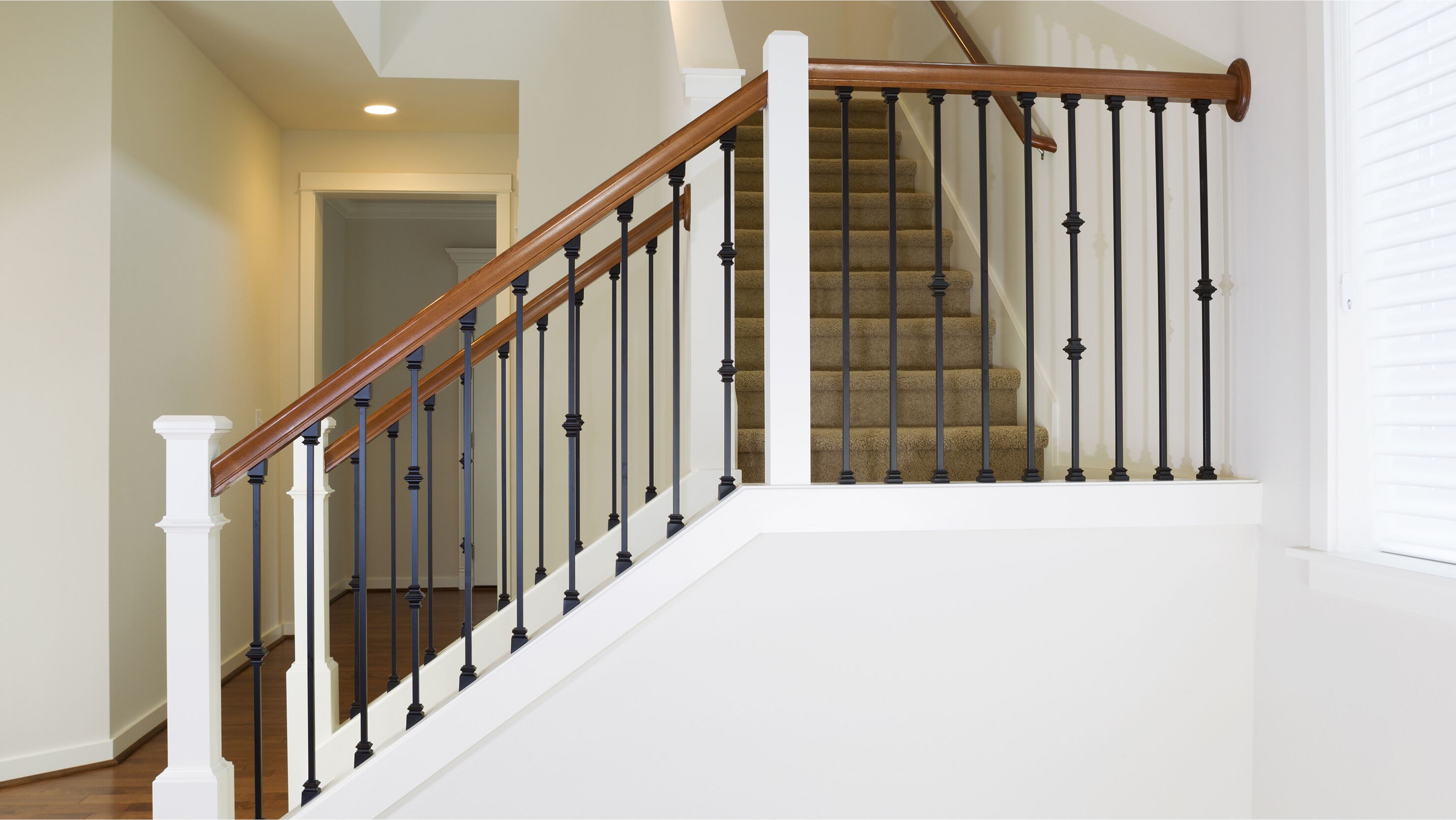 Living room with a staircase featuring slim metal rails and a light wood handrail.