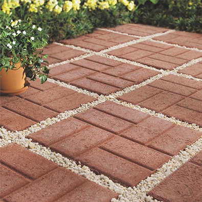 A brick patio with square patterned pavers and gravel fill.