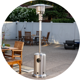 An upright stainless steel gas heater on a patio enclosed by a white fence.