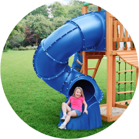 A little girl playing on a playset with a blue tube slide.