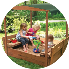 Children playing in a canopy-covered sandbox with 2 bench seats.