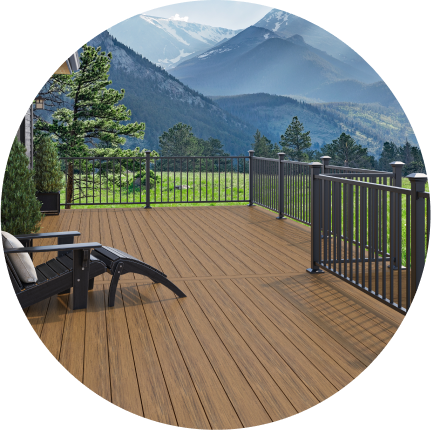 An Adirondack chair on a deck with brown Voyage decking and black railing with a view of mountains.