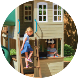 Children playing on a two-story outdoor playhouse with a first-story kitchen area.