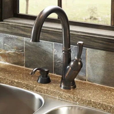 A high-arc bronze kitchen faucet over a sink.