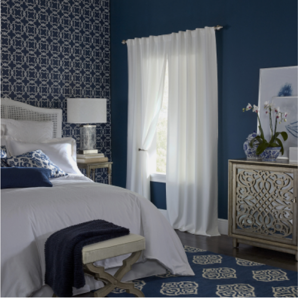 A white and navy blue bedroom with white light filtering curtains.