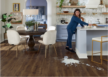 Spilled milk on medium brown wood-look laminate floors in a kitchen.