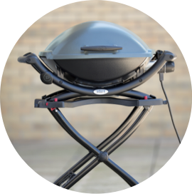 A black Weber Electric Grill plugged in on a patio.