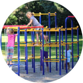 Kids climbing on a blue, yellow and red metal jungle gym playset.