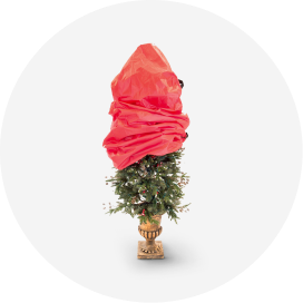A red Christmas tree storage bag partially covering an artificial tree in a gold stand.