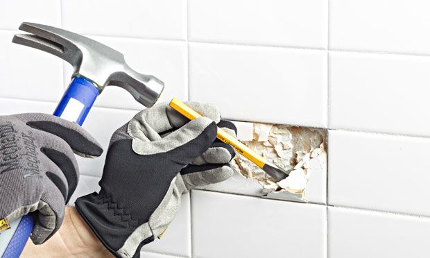 Breaking away tile with chisel.