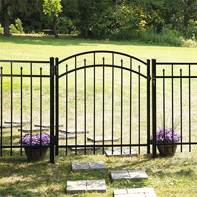 Two black gate posts supporting a gate on an aluminum fence.