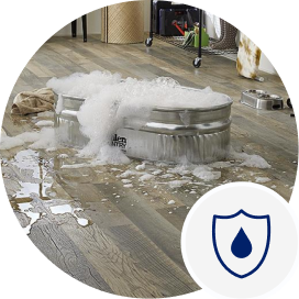 A small tin tub full of bubbly water that’s splashed onto a gray laminate wood-look floor.