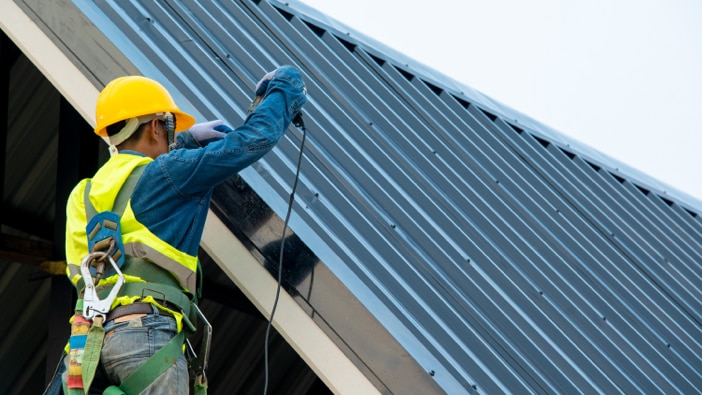 Roofing professional installing metal roof panels.