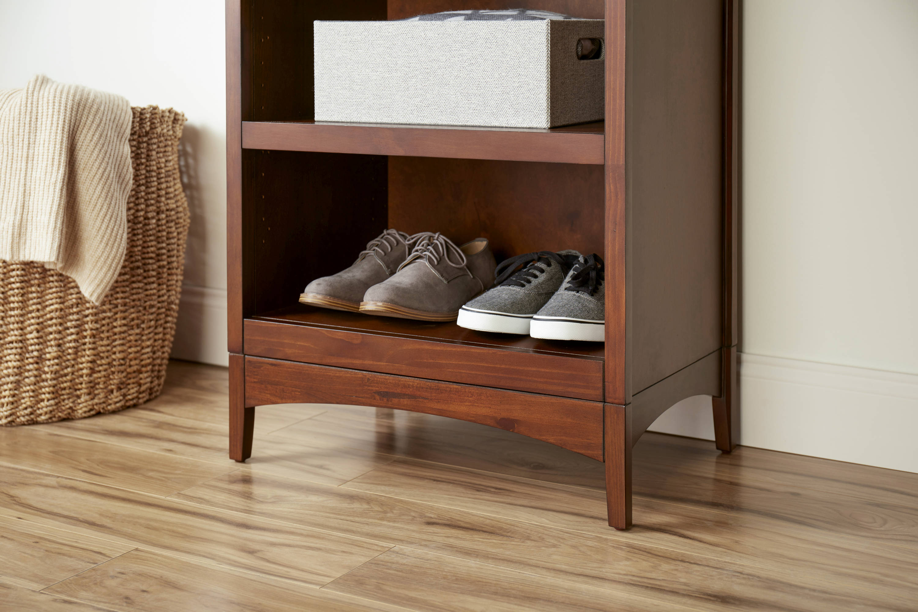Large white walk-in closet features floor-to-ceiling custom shoe shelves  and a light tan bench.