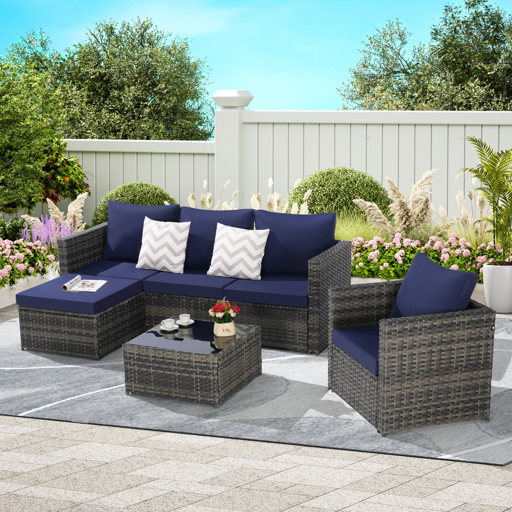 Outdoor wicker patio seating set with blue cushions on a rug