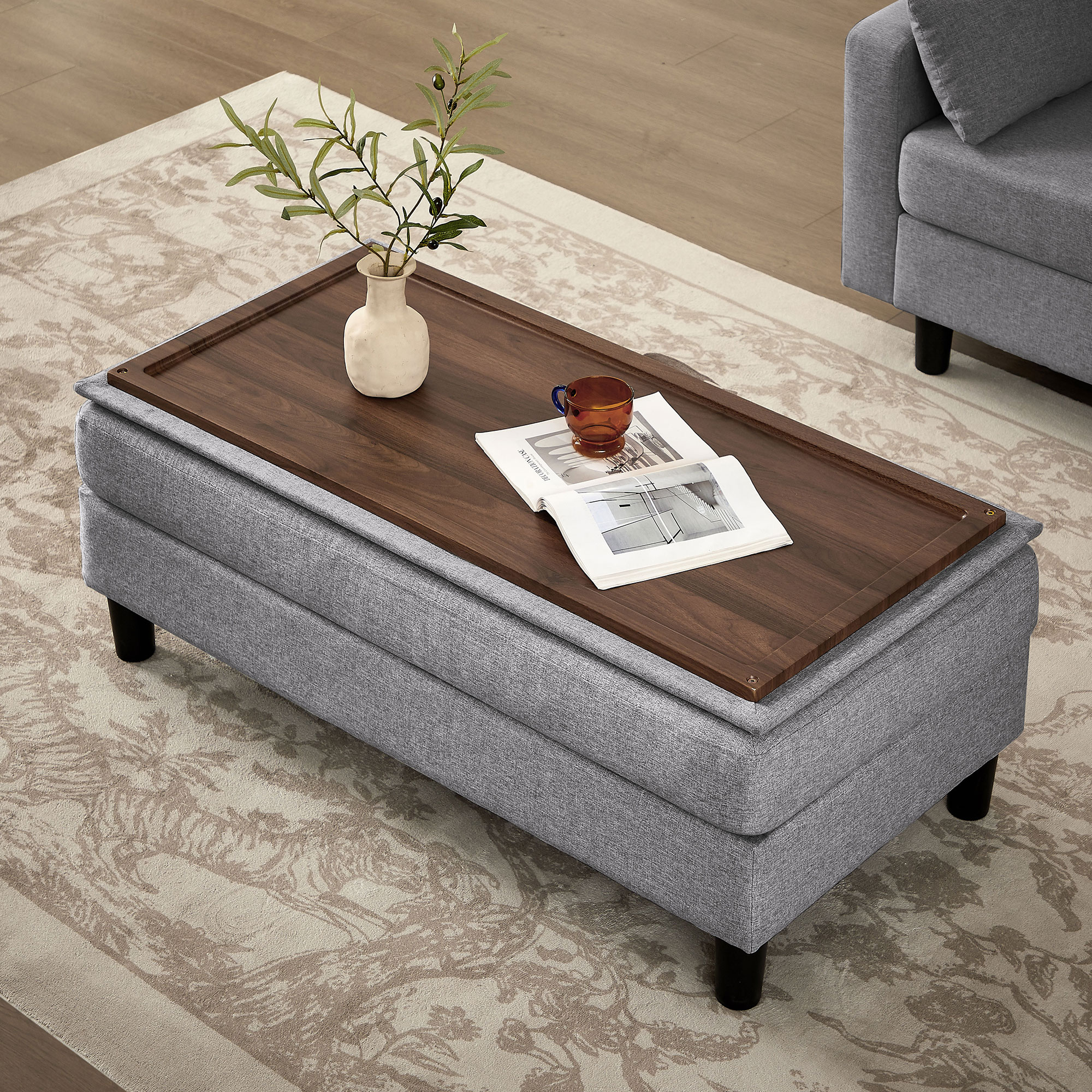 Wood-topped ottoman coffee table in front of grey sofa