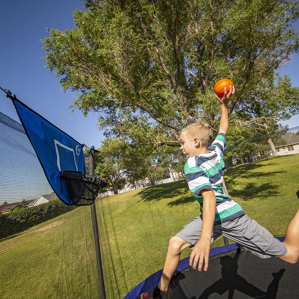 A kid about to dunk on a Skywalker Trampoline Basketball Hoop. 